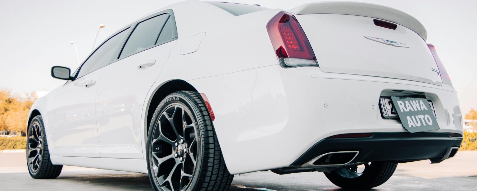 A rear view of a sleek white Chrysler 300 parked in sunny Erbil, Iraq.