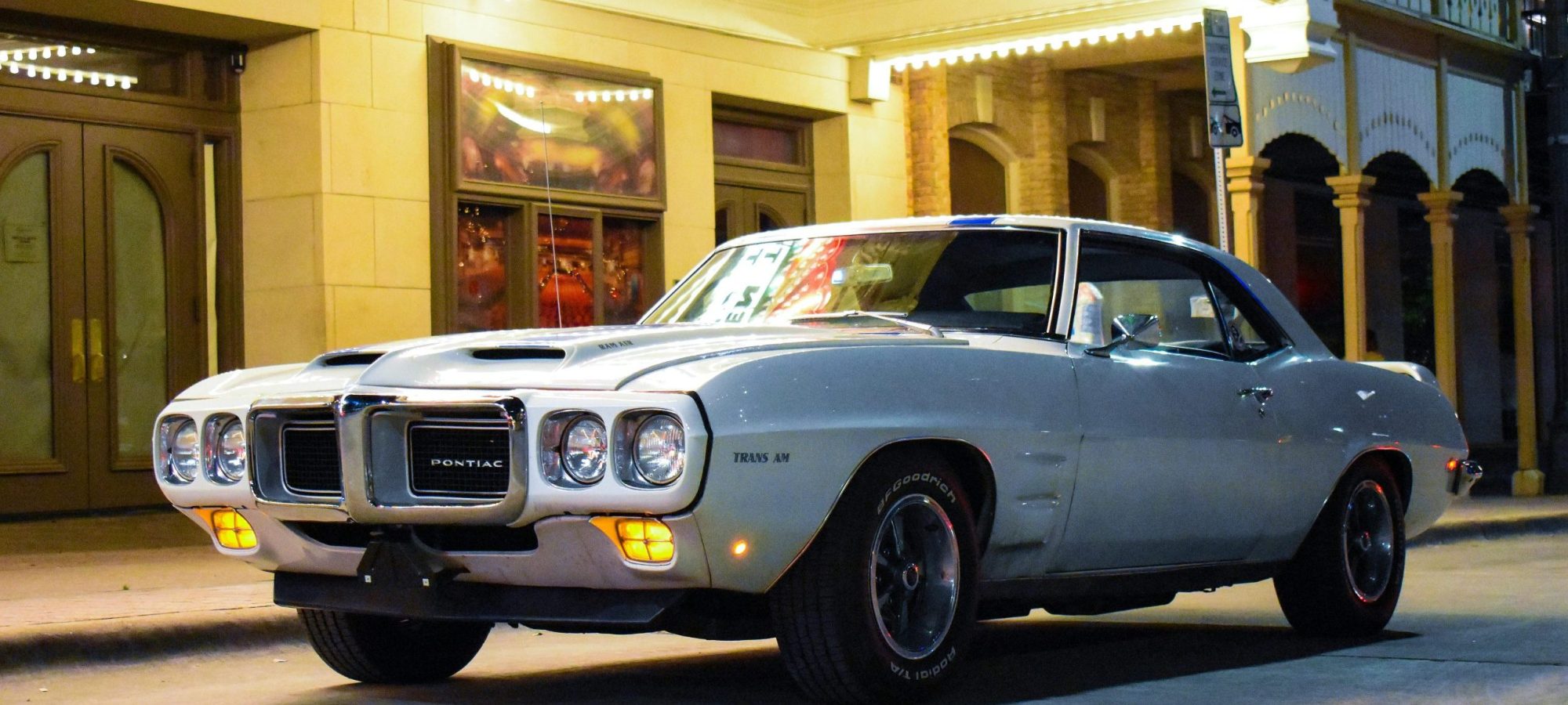 Vintage Pontiac Firebird Trans Am parked on a lit street at night.