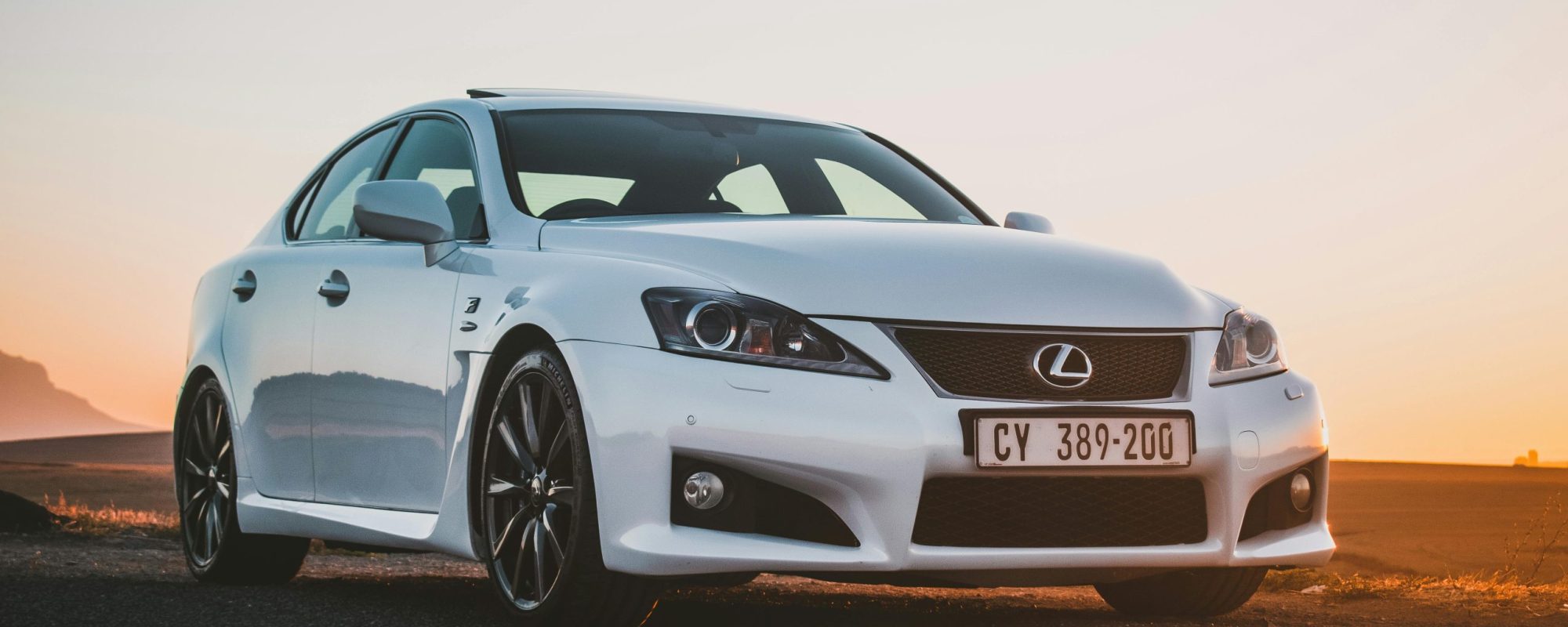 A white Lexus sedan parked on an expansive rural road at sunset. Lexus Spacers & Adapters